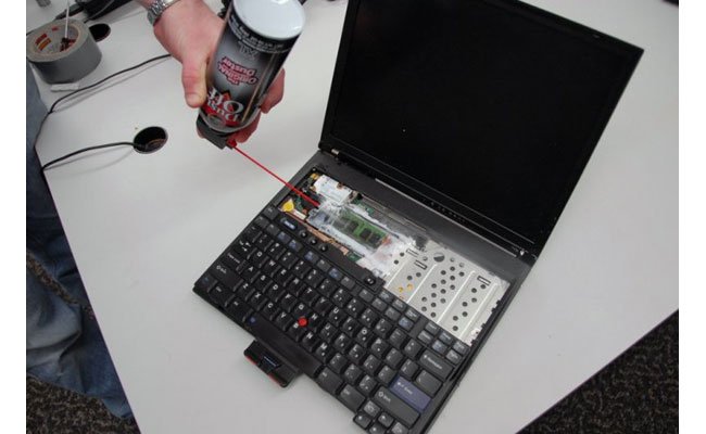 A person using a cold spray to freeze the RAM of a laptop, highlighting the risk of cold boot attacks for BitLocker Security.