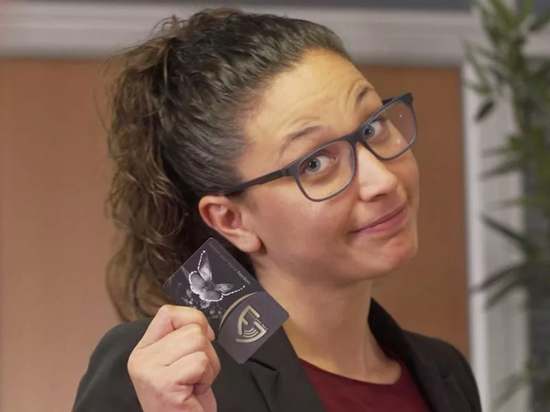 A young woman presenting her EviCard NFC HSM, a credit card-sized NFC hardware security module for PassCypher, DataShielder, SeedNFC products.
